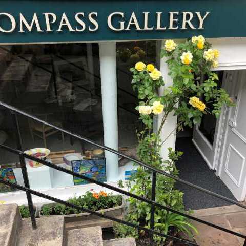image of the gallery front with steps leading down and a yellow rose bush by the door