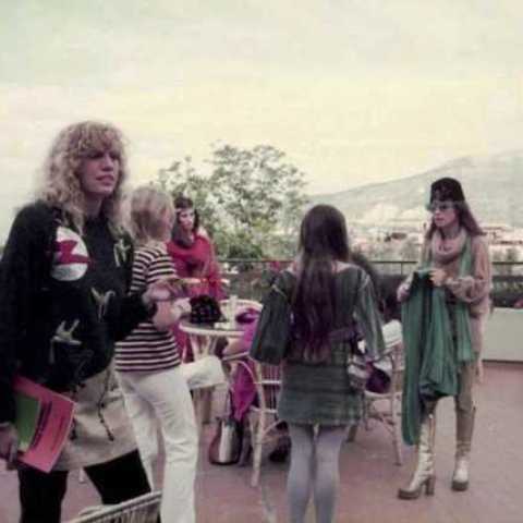 A group of women in 1970's dress on a terrace in Naples, with mountain and volcano landscape in the background