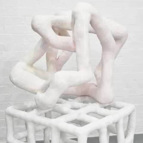 Pale pink sculpture that resembles bent tubes/wire sat on a box made of ceramic white tubes