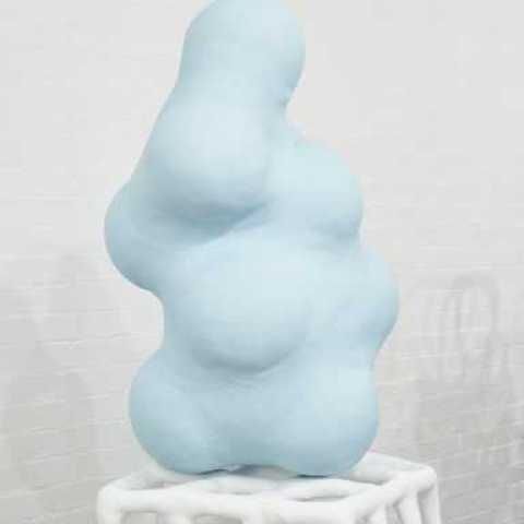 Pale Blue blob-like sculpture sat on a grid/white tube-like box