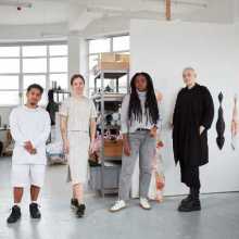 The Image depicts four Acme artists standing next to each other in their studio at Warton House, London. Artists from left to right: Bryan Giuseppi Rodriguez Cambana, Kristīne Daukšte, Lisa-Marie Harris, Holly Buckle.  