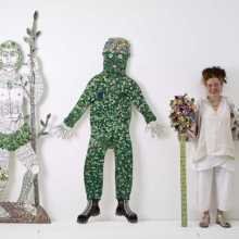 artists next to two life size sculptures and holding two flowers bunches