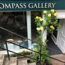 image of the gallery front with steps leading down and a yellow rose bush by the door