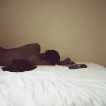 Person laid on a white sheet, next to a hat and book