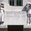 Entrance sculpture to RADA. Two figures with theatrical masks either side of a sign in grey stone. 